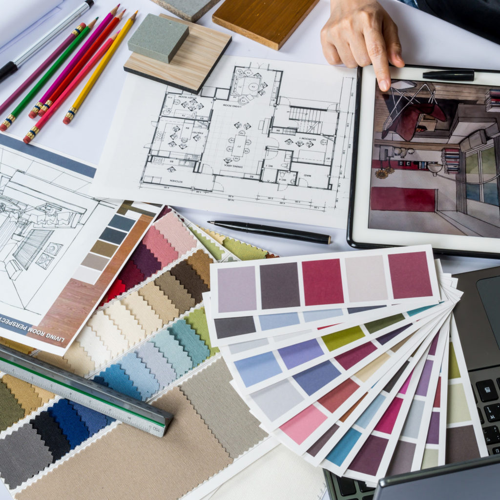 Top view of architects/ interior designer hands working with tablet computer, material sample on desk