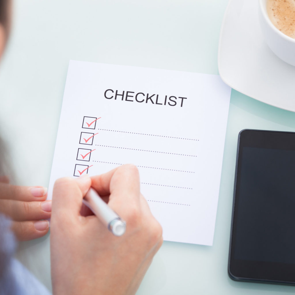 High Angle View Of A Businesswoman Marking On Checklist At Desk